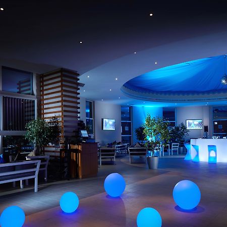 Grand Millennium Al Wahda Hotel And Executive Apartments Abu Dhabi Exterior photo The photo depicts a modern interior space, likely a lounge or reception area. The lighting is predominantly blue, creating a calm and inviting atmosphere. There are several large, glowing blue spheres placed on the floor, which add a decorative eleme