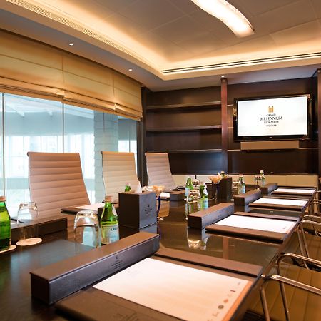 Grand Millennium Al Wahda Hotel And Executive Apartments Abu Dhabi Exterior photo The photo displays a modern conference room featuring a long, dark wooden table with several ergonomic chairs arranged around it. There are notepads and pens placed in front of each chair. In the background, there is a large screen mounted on the wal