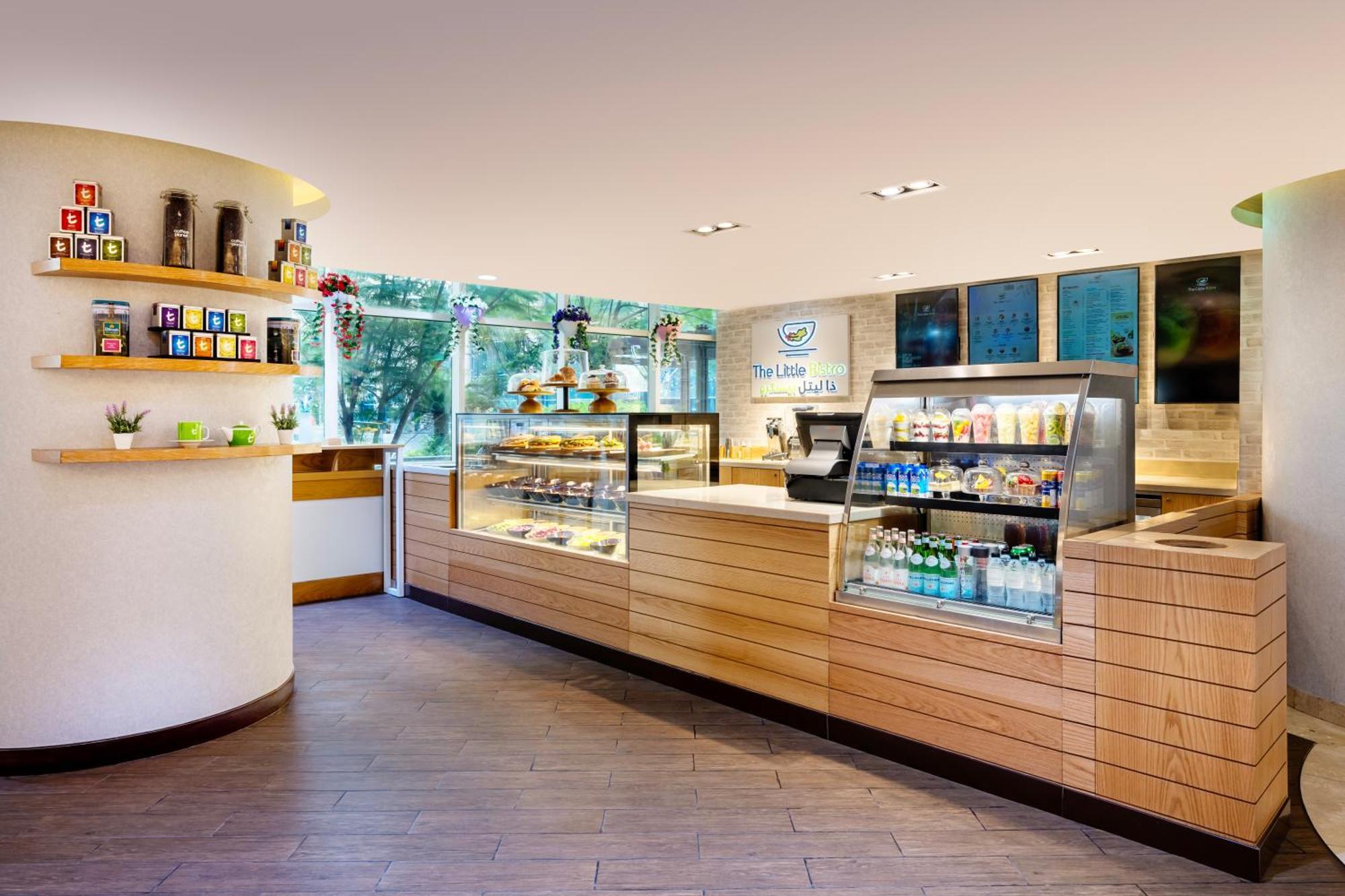 Grand Millennium Al Wahda Hotel And Executive Apartments Abu Dhabi Exterior photo The photo shows the interior of a café or tea shop. It features a well-designed counter with wooden panels and glass displays showcasing various drinks and pastries. There are shelves on the wall containing jars or containers, presumably for differen